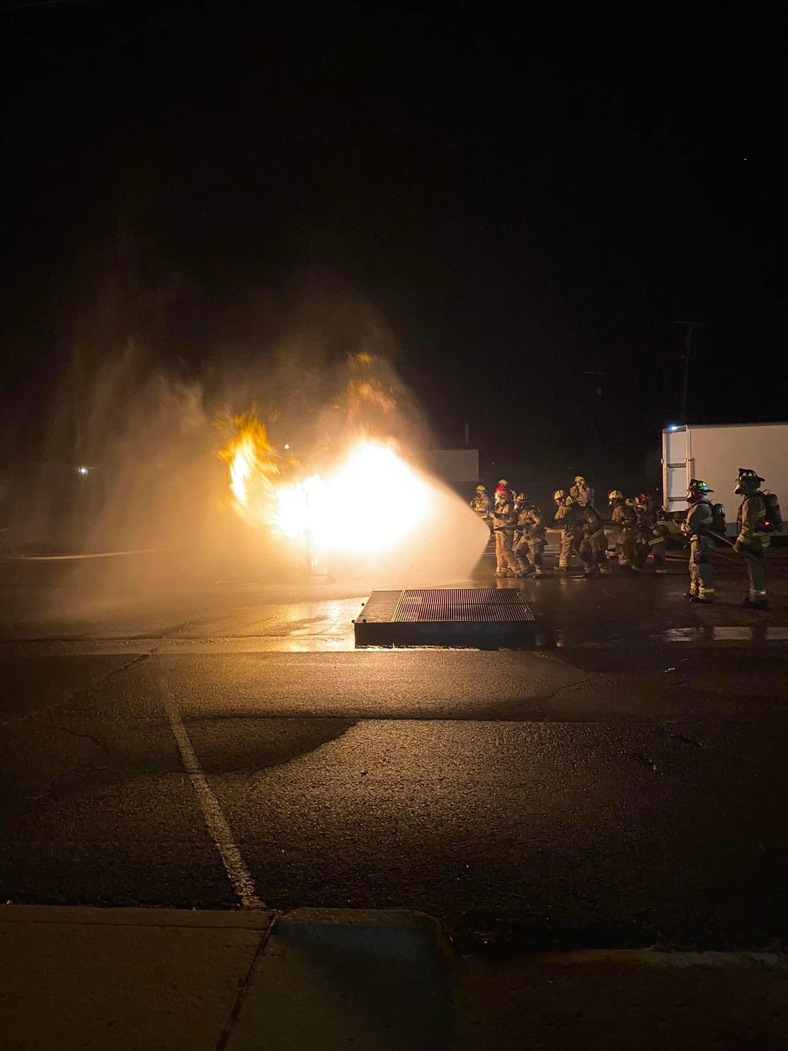 Fire fighters use a chemical spray to extinguish a flammable gas fire during a training session after dark. 