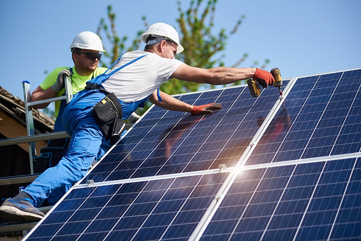 Stock image of electricians installing rooftop solar.