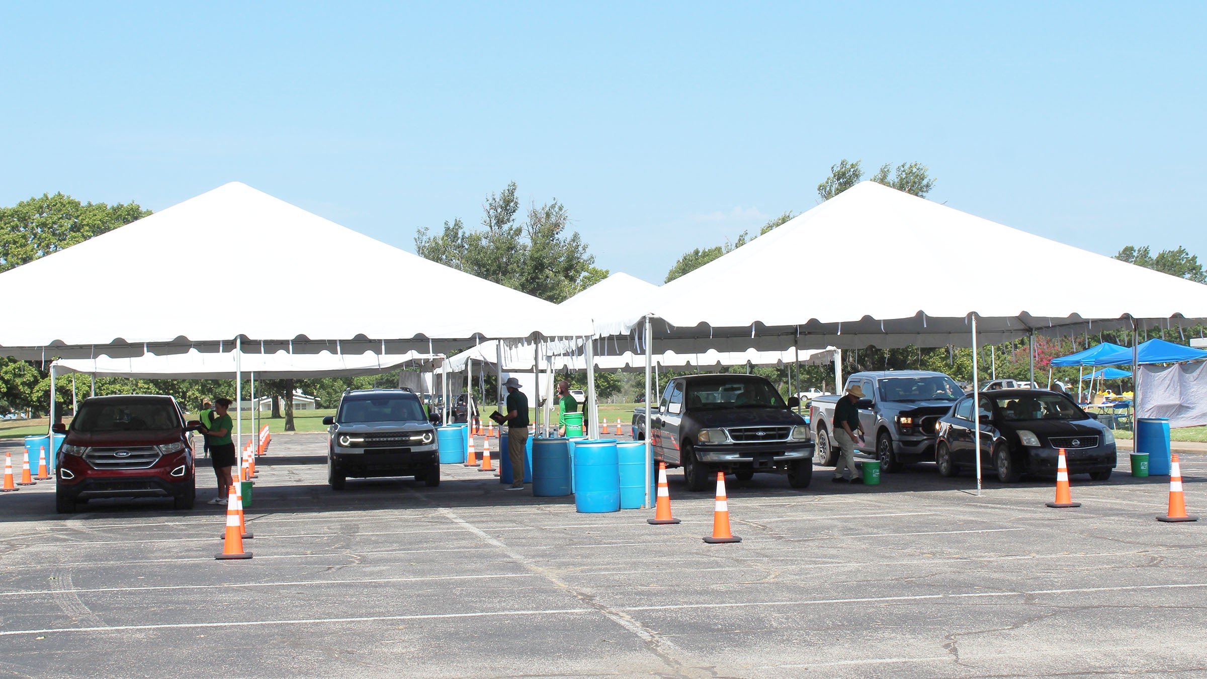 Photo of tents set up in a parking lot and with lines of cars passing under them for voting and registration.