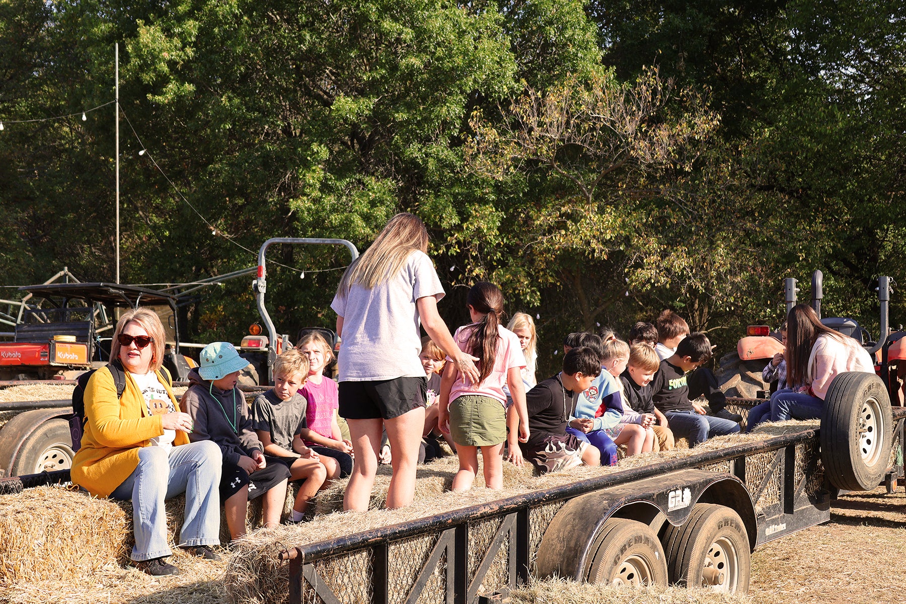 Kids and teachers on a a trailer bed full of hay for a hay ride. 