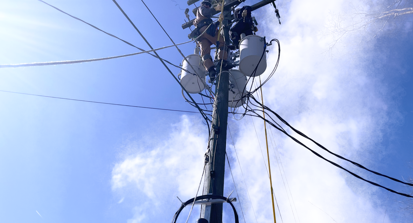 Two East Central Electric lineman work while standing on a power pole, providing mutual aid in Mississippi.